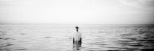 Eine Person steht im Meer. Schwarz/Weiß Bild.